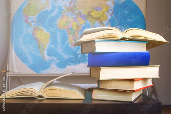 Obraz Composition of books and studies on table with world map hanging on wall