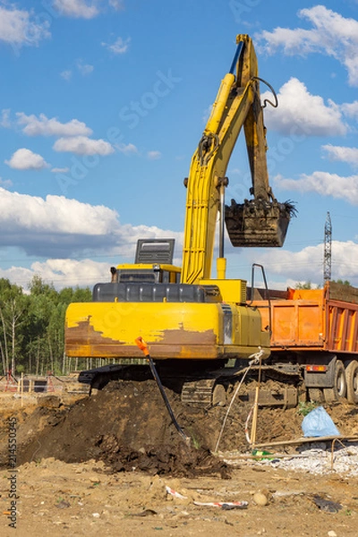 Fototapeta Excavator load the earth into a dump truck