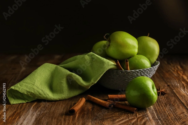 Fototapeta Bowl with fresh apples and cinnamon on wooden table