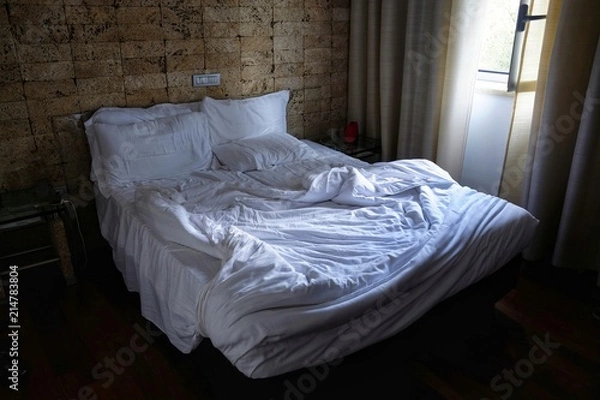 Fototapeta empty bed and unmade at the first light of dawn