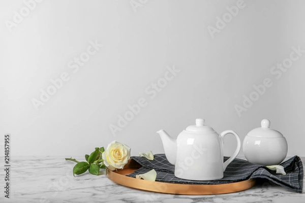 Obraz Tray with teapot and rose on table against light background
