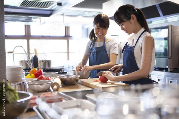 Fototapeta 料理教室で友人と一緒に料理を作る女性二人