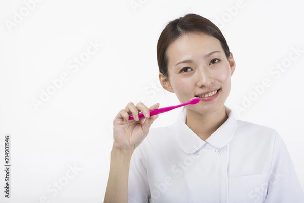 Obraz 歯ブラシを持って微笑む白衣とピンクのエプロンを着た女性