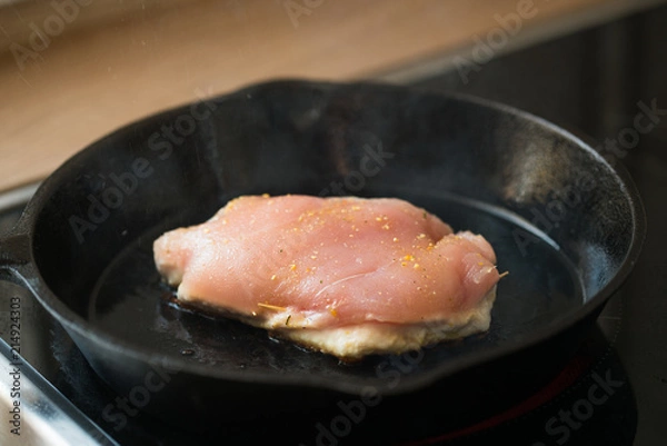 Obraz One of the steps in preparation of a raw stuffed chicken breast in a cast-iron pan ; grilling the meat.