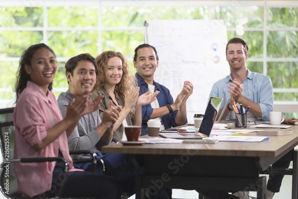 Fototapeta Group of Asian and caucasian businessmen is meeting his work. And happily smile at their job. In the modern office. There is poster board behind.