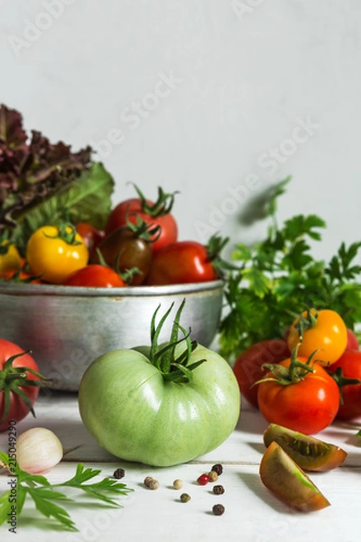 Fototapeta Fresh tomatoes and parsley, dill, garlic on a light background in a rustic kitchen and wooden utensils still life with a copy space