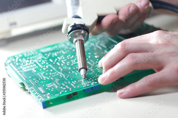 Fototapeta Engineer repair circuit board with Electric Vacuum Solder Sucker Desoldering Pump
