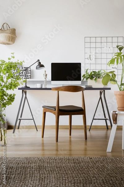 Fototapeta Wooden chair at desk with lamp and computer desktop in home office interior with plants. Real photo