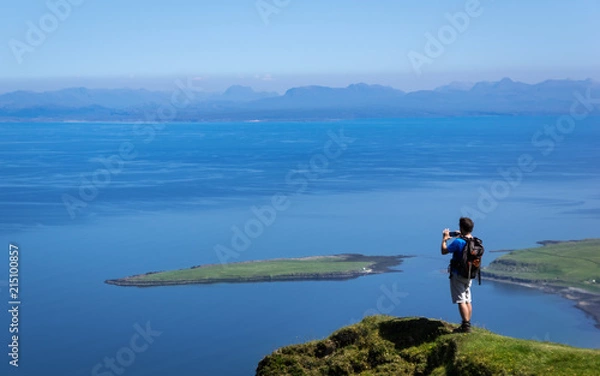 Fototapeta Man Taking Picture at Cliff on Quiraing Trail in Summer Skye Scotland UK