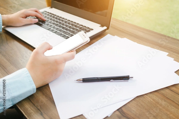 Fototapeta Close-up of Business woman working with smartphone,laptop and document in coffee shop like the background.