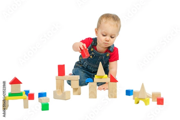 Fototapeta Little cute boy builds houses out of colored blocks