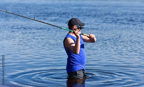 Fototapeta The guy throws the spoon into the river spinning. Fisheries on the river.