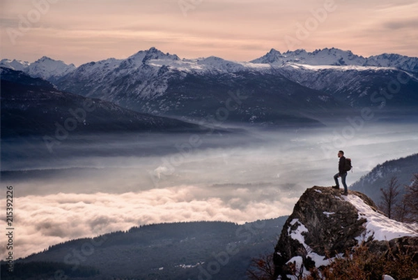 Fototapeta Man hiker looking mountain landscape with fog standing on a rock in Patagonia Argentina