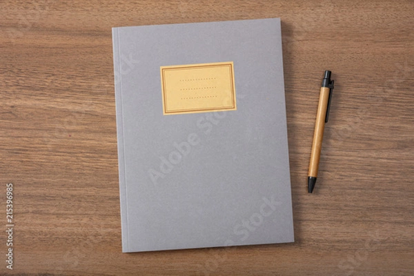 Fototapeta Grey school notebook or diary, old fashioned, on wooden desk, blank label, space for text, top view