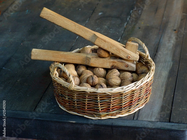 Fototapeta Nutcracker in a basket with walnuts.