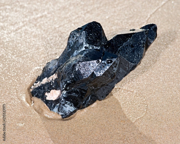 Fototapeta Morion Smokey Quartz with Chlorite lying on wet sand  in front of the lake at sunrise.