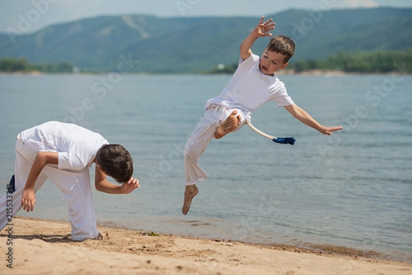 Fototapeta Training of two children on the beach: capoeira, sports