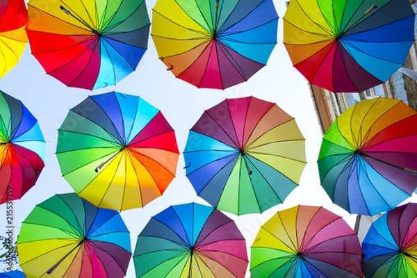 Fototapeta Multi-colored umbrellas background. Colorful umbrellas floating above the street. Street decoration.