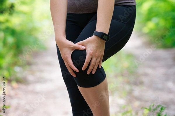 Obraz Pain in woman's knee, massage of female leg, injury while running, trauma during workout