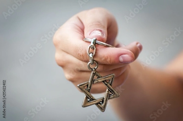 Fototapeta Young woman's hand holding a David Star ("Magen David") key chain. The State of Israel, Judaism, Zionism concept image.