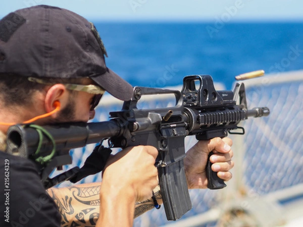 Obraz Man shooting rifle,shell ejecting