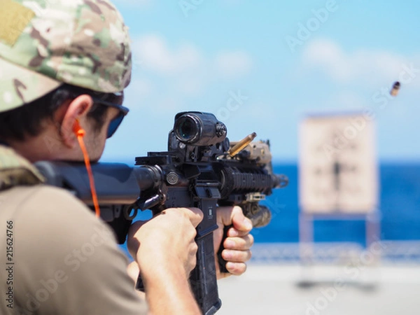 Obraz Man shooting rifle,shell ejecting