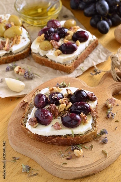 Fototapeta Crostini with roasted grapes, goat cheese, walnuts and honey, vertical