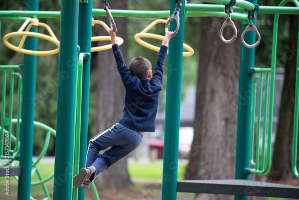 Fototapeta Boy child on monkey bars in the park playground.
