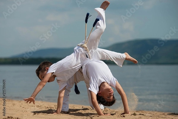 Fototapeta Training of two children on the beach: capoeira, sports