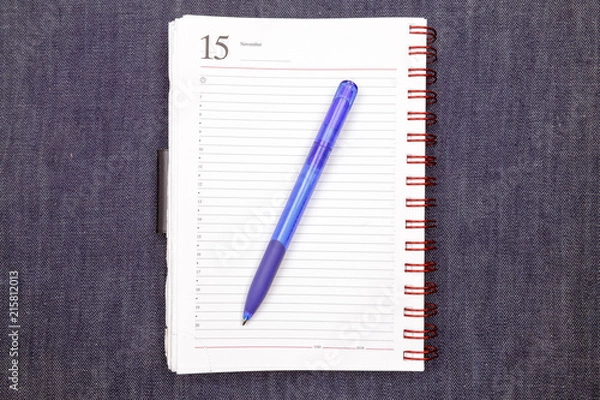 Obraz Notebook with pen on jeans texture