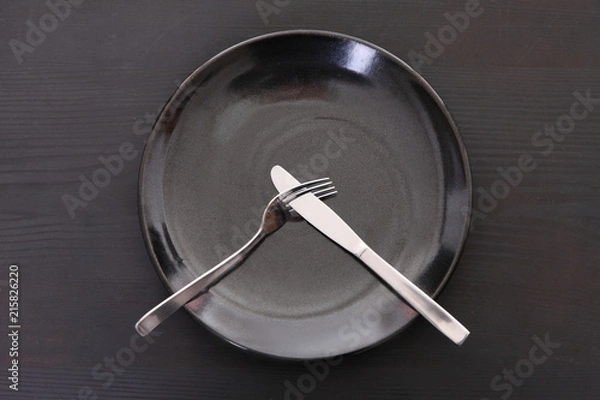 Fototapeta 
黒い木製テーブルに置かれた黒い皿とカトラリーによる不満足の合図