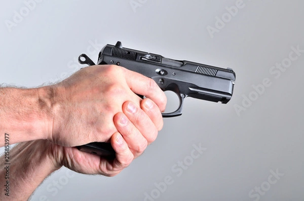 Fototapeta Hand of man aiming with a pistol - side view