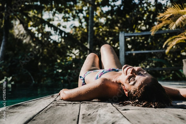 Fototapeta .Young and pretty woman enjoying her vacation in Ubud, in the Bali island, Indonesia. A summer afternoon in the pool with a tropical background. Relaxed and happy attitude. Lifestyle.