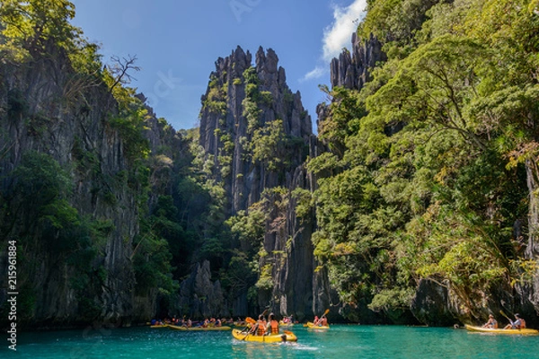 Fototapeta National Park and Reserve El Nido Palawan, Philippines. Tourists are kayaking in the small lagoon of Miniloc island