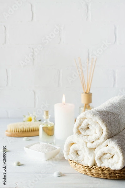 Fototapeta Tło aromaterapii SPA. Martwa natura z białym ręcznikiem, olejkiem do kąpieli, szczotką do masażu i świecą.