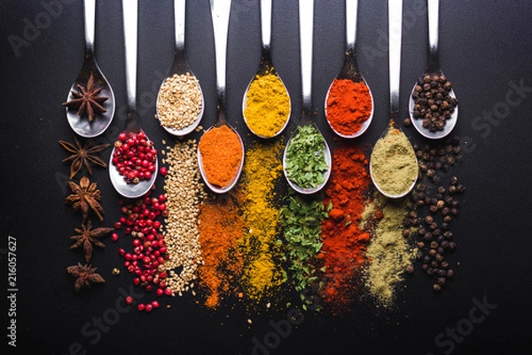 Fototapeta Spices and condiments for cooking on a black background