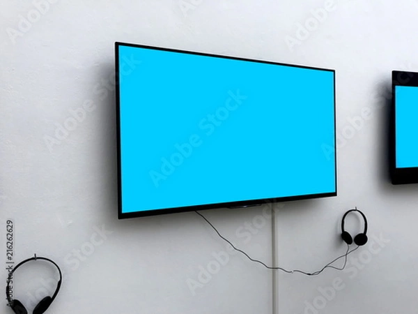 Fototapeta  Blank screen LED TV with heaphones Gaming and entertainment concepts hanging on white background for billboard information or banner background use