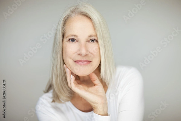 Fototapeta stunning beautiful and self confident best aged woman with grey hair smiling into camera, portrait with white background 