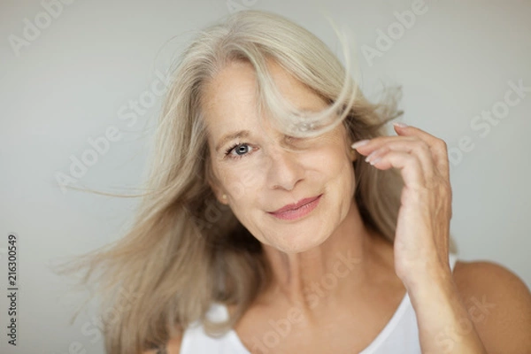 Fototapeta stunning beautiful and self confident best aged woman with grey hair smiling into camera, portrait with white background 