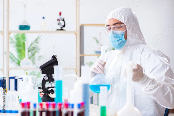 Fototapeta Young chemist student working in lab on chemicals