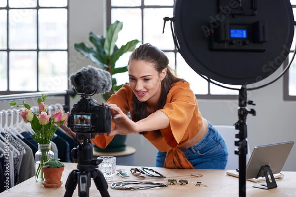 Fototapeta Online content creator vlogger adjusting her recording equipment