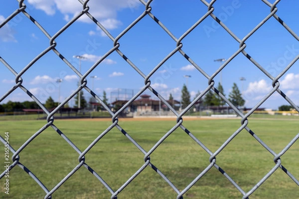 Fototapeta Chain link fence with baseball field background