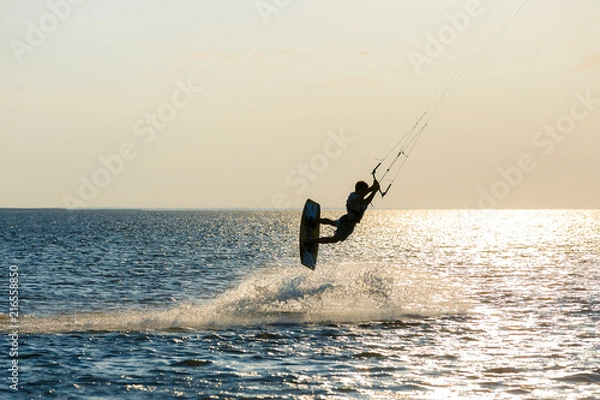 Fototapeta professional kiter doing a complicated trick on a beautiful sunset background