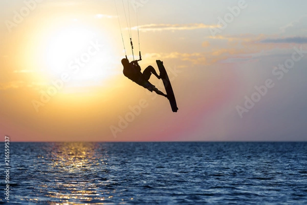 Fototapeta professional kiter doing a complicated trick on a beautiful sunset background