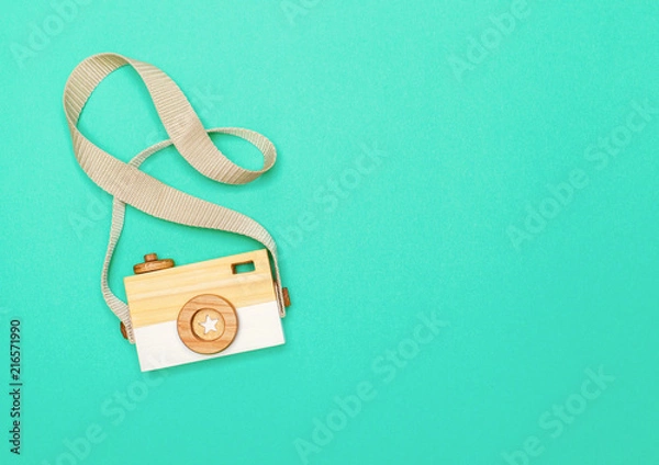 Fototapeta view from above on a wooden children's handmade camera on a bright colored paper background with space for text. flat lay