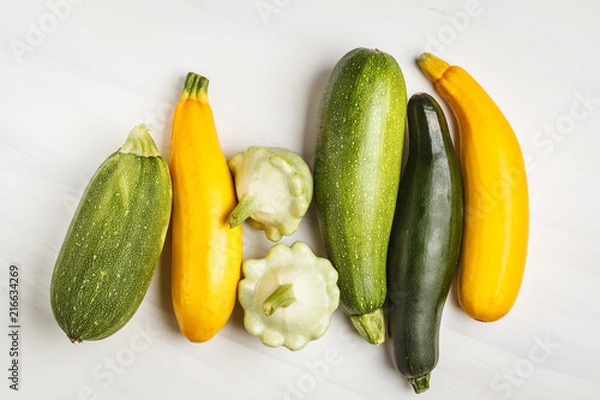 Obraz Different kinds of zucchini on white background, top view, copy space. Healthy clean eating concept.