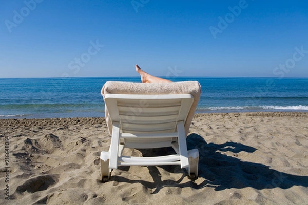 Obraz A man is resting on a deckchair by the sea.