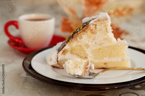 Fototapeta Dessert in a small spoon. A piece of cake in a dessert spoon. Cake on a silk tablecloth. Dessert in the form of a cake with the name of a turtle. A cake, a cup of tea and glare.