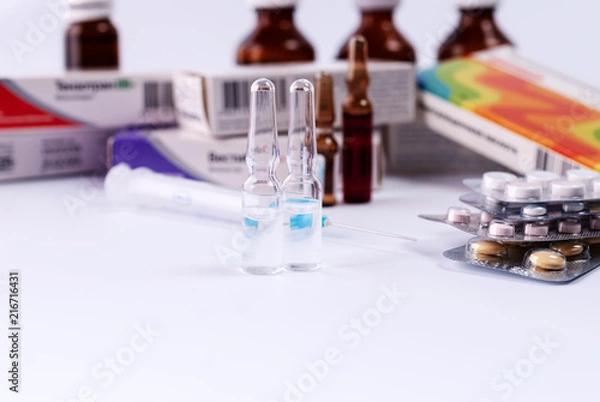 Fototapeta Ampoules on the background of packs with medicines. Medical concept