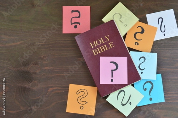 Fototapeta Święta Biblia i kolorowe notesy ze znakami zapytania na brązowym drewnianym tle jako symbol odpowiedzi, których możesz znaleźć w Biblii lub fragmentach, których nie rozumiesz